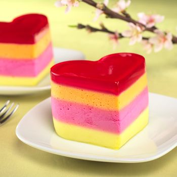 Colorful Peruvian heart-shaped jelly-pudding cakes called Torta Helada with a blooming peach branch in the back (Selective Focus, Focus on the front of the first cake)
