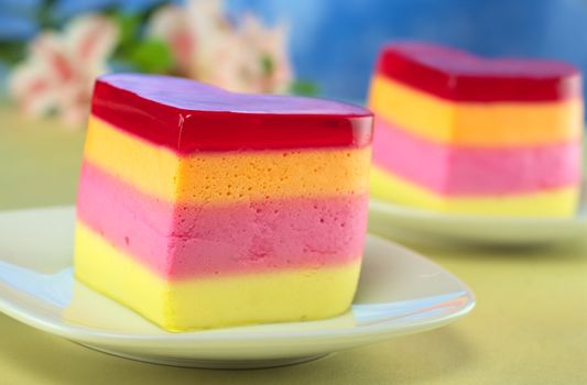 Colorful Peruvian heart-shaped jelly-pudding cakes called Torta Helada with inca lily in the back (Selective Focus, Focus on the front of the first cake)