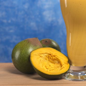 Fruit called Lucuma (lat. Pouteria lucuma) grown in the Andean region of Peru, which is very popular in Peru, with a milkshake made of lucuma beside (Selective Focus, Focus on the front)