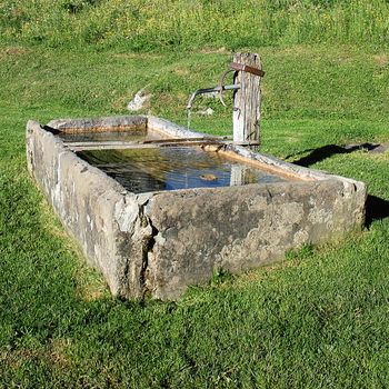 Fountain with drinking water and grass in alpine mountain 