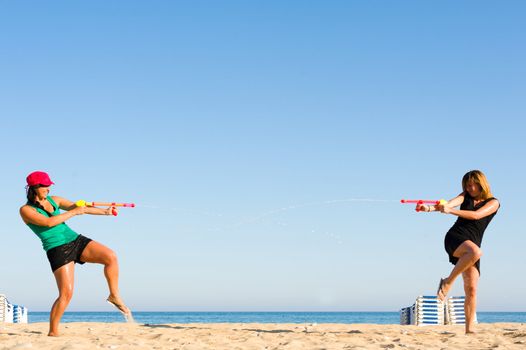 Girls with water pistols fooling around on the beach