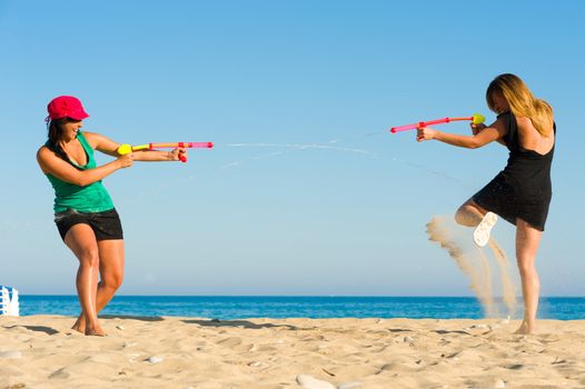 Girls with water pistols fooling around on the beach