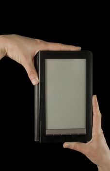 Hands holding an electronic book reader on the black background