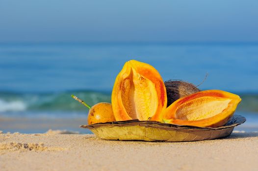 Exotic tropical fruit on the leaves plate on the sand