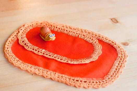 A toy snail on orange napkins on table
