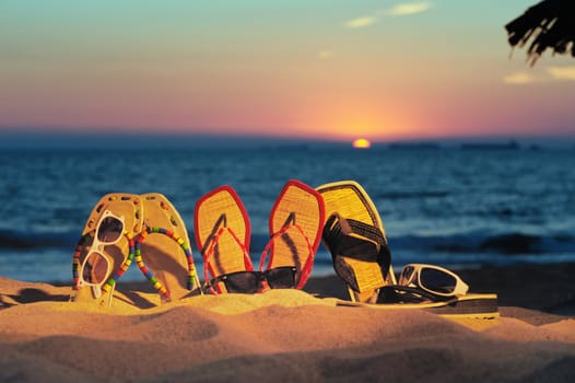 Beach sandals and glasses on the beach in evening