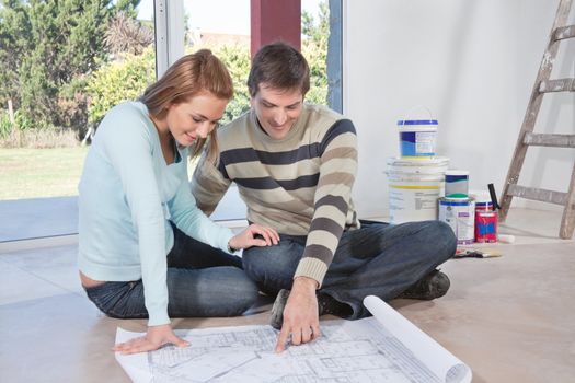 Mature man showing blueprint of their new house to his wife