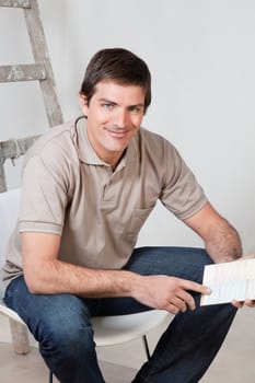 Portrait of happy mature man holding color swatch in his hand