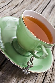 Green antique tea cup with healthy organic tea on a rustic background