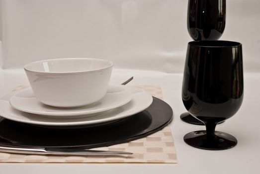 Service plates in black and white, with plate, glasses, cutlery