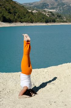 Fit and balanced woman doing a yoga handstand outdoors