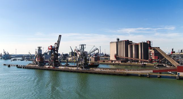 Grain elevator in harbour with terminal and cranes for transhipment and ships getting loaded