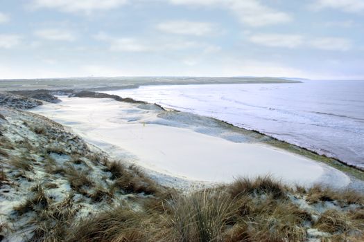 atlantic ocean beside a snow covered links golf course in ireland in snowy winter weather