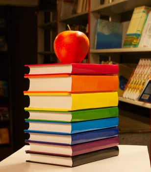 Pile of colorful books with an apple on it