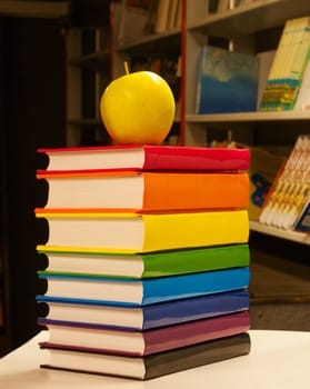 Pile of colorful books with an apple on it