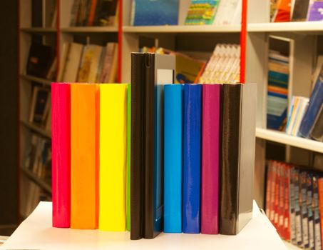 Row of colorful books and electronic book reader in the book shop