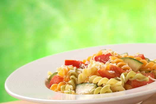 Colorful fusilli pasta with zucchini and tomato and grated cheese (Selective Focus, Focus one third into the meal)