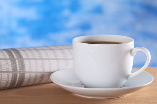 Hot coffee with newspaper (stock market section) and blue background (Selective Focus, Focus on the front of the coffee cup)