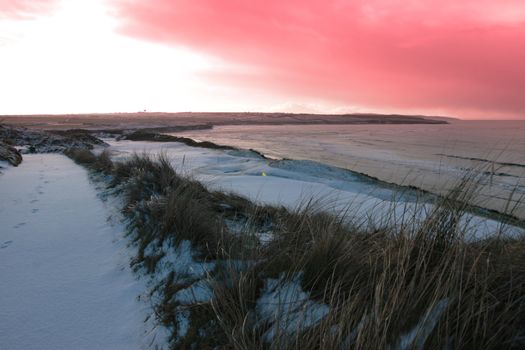 a snow covered links golf course in ireland in winter weather at sunset