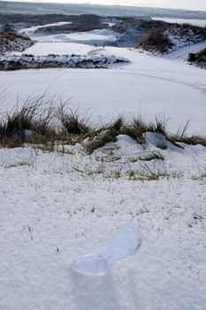 a crystal glass slipper in a snow covered irish golf course for a concept on ladies golf