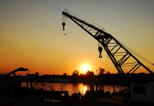 silhouettes on crane in port of Sava river over orange sunset in Belgrade, Serbia