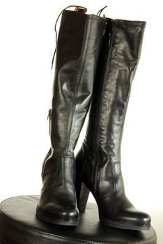 pair of female black leather fashionable boots over white background