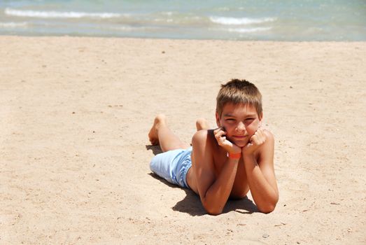 caucasian boy lying on the sand beach in Egypt