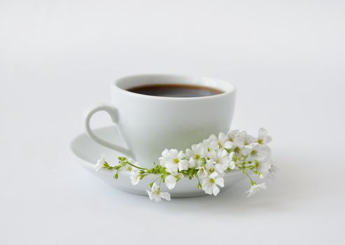 A cup of black coffee with flowers on a gray background
