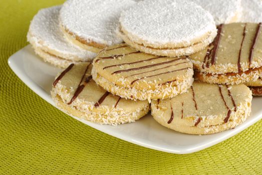 Peruvian cookies called Alfajor, which are filled with a caramel-like cream called Manjar, served on a white plate on a green table mat (Selective Focus, Focus on the front)