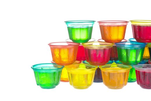 Colorful jellies in plastic bowls arranged like a pyramid on white 