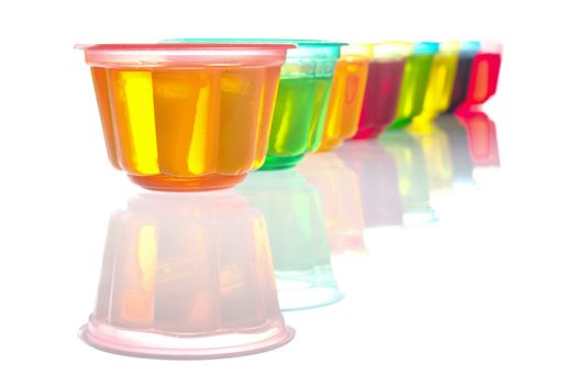 Colorful jellies in plastic bowls arranged in a row on white (Selective Focus, Focus on the first jelly) 