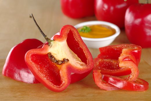 Cutting Peruvian hot pepper called rocoto on a cutting board with salsa in the back (Selective Focus, Focus on the slices on the right and the seeds of the rocoto on the left)