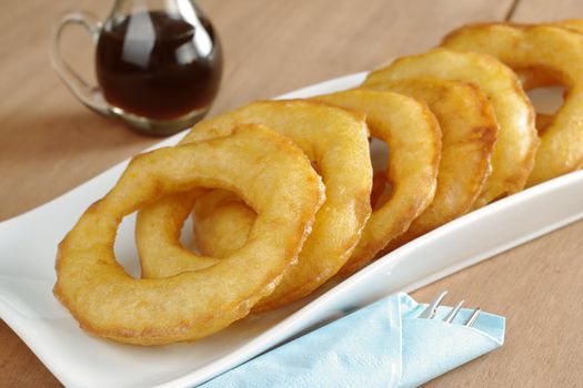 Popular Peruvian dessert called Picarones made from squash and sweet potato and served with Chancaca syrup (kind of honey), which can be seen in the back (Selective Focus, Focus on the lower part and right side of the first ring)