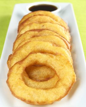 Popular Peruvian dessert called Picarones made from squash and sweet potato and served with Chancaca syrup (kind of honey), which is the black sauce in the back (Selective Focus, Focus on the upper part of the first ring)