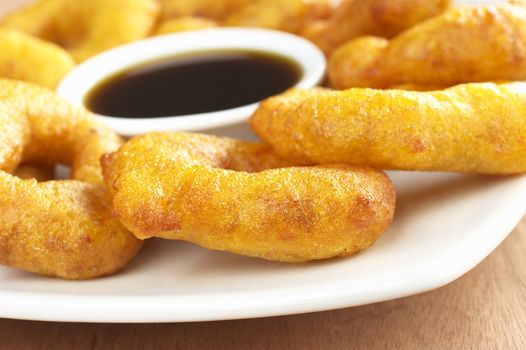 Popular Peruvian dessert called Picarones made from squash and sweet potato and served with Chancaca syrup (kind of honey) (Selective Focus, Focus on the front)