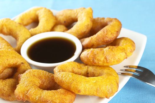 Popular Peruvian dessert called Picarones made from squash and sweet potato and served with Chancaca syrup (kind of honey) (Selective Focus, Focus on the front)