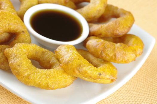 Popular Peruvian dessert called Picarones made from squash and sweet potato and served with Chancaca syrup (kind of honey) (Selective Focus, Focus on the front)
