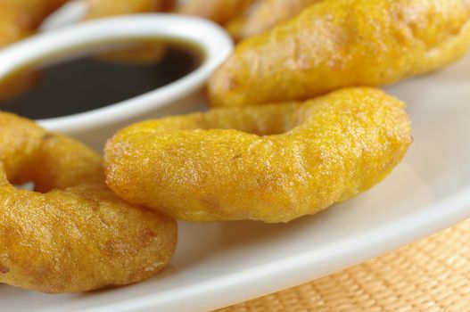 Popular Peruvian dessert called Picarones made from squash and sweet potato and served with Chancaca syrup (kind of honey) (Selective Focus, Focus on the front)