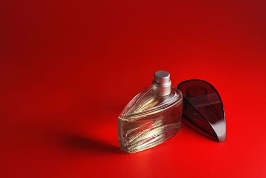 perfume. A bottle perfume on a red background with effective illumination