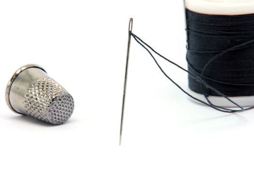 sewing items needle  thread and thimble isolated on white background