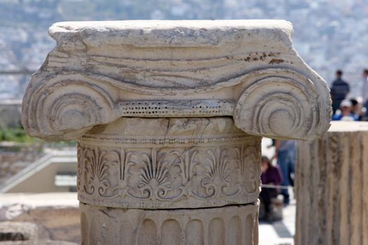 closeup detail from ancien pillar in the archaeological site of parthenon athens greece with blur tourists and city in background