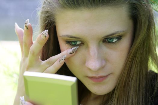 The girl corrects for a make-up around of eyes