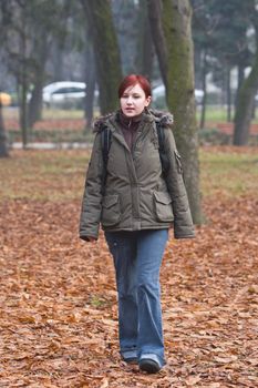 Redheaded backpacker girl walking in an autumn park.Shot with Canon 70-200mm f/2.8L IS USM