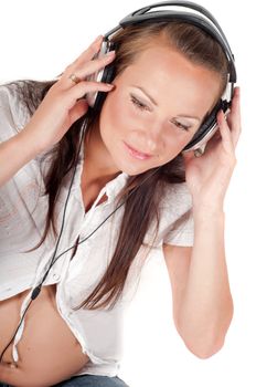 Beautiful pregnant woman with headphones in studio isolated on white