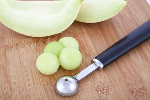 Fresh Honeydew melon balls on cutting board with melon baller
