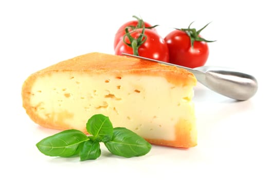 a piece of soft cheese with basil on a white background