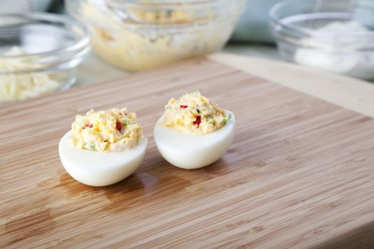 Thow deviled eggs on cutting board with ingredents in background.