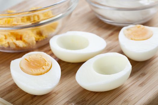Two hard boiled eggs cut in half with yolk in bowl.
