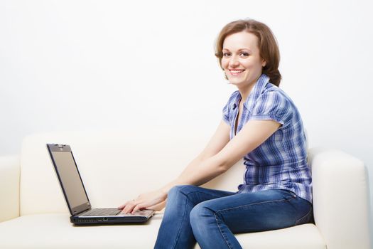 young slender woman with a laptop sitting on the couch