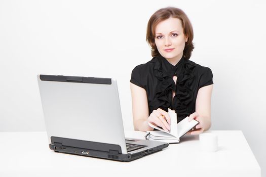 smiling slender business attractive girl with a laptop and a notebook in the office
